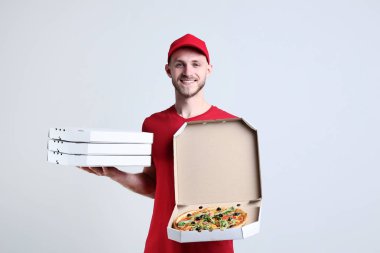 Karton kutular gri arka plan üzerinde pizza ile tutarak teslimatçı
