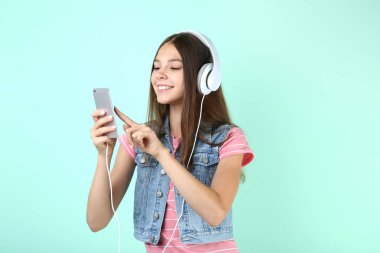 Akıllı telefon tutarak ve kulaklıklar nane arka planda müzik dinlemek genç kız