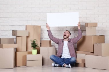 Karton kutular ve pano tuğla duvar zemin katta oturan genç adam