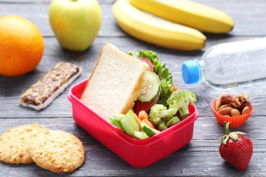 Sandviç ve sebze ahşap masa üzerinde okul öğle yemeği kutusu