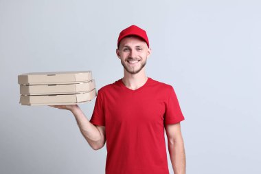 Pizza kutuları gri arka plan üzerinde tutarak teslimatçı