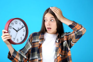 Mavi arka plan üzerinde saat tutan genç Genç kız