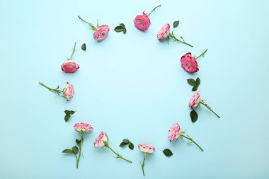 Mavi arka plan üzerinde daire şeklinde yeşil yaprakları ile pembe gül çiçek