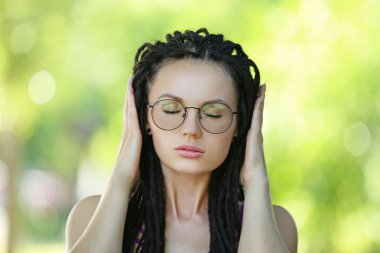 Sevimli genç kadın Parkı kapalı gözler ile ayakta güneş gözlüğü takıyor dreadlocks ile