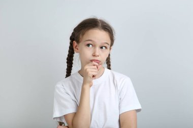 Gri arka plan üzerinde beyaz t-shirt sevimli dalgın kız