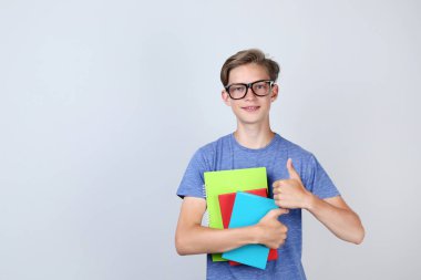 Kitap tutan ve başparmak gri arka plan üzerinde gösterilen genç çocuk