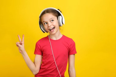 kulaklıklar müzik dinlemek ve barış sembolü sarı arka plan üzerinde gösterilen mutlu küçük kız