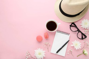 Çiçek fincan kahve ve pembe bir arka plan üstünde defter ile şapka ile