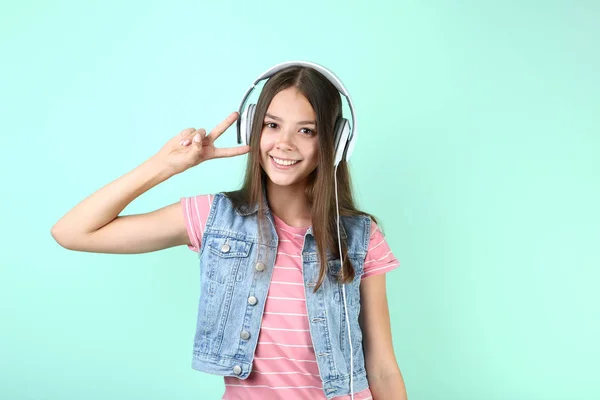 年轻女孩听音乐在耳机和显示和平标志在薄荷背景 — 图库照片