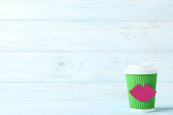 Cup of coffee with paper lips on wooden table