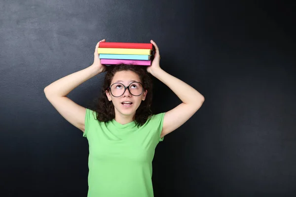 Hermosa Joven Sosteniendo Libros Cabeza Posando Fondo Pizarra — Foto de Stock