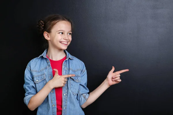 Kleines Mädchen Jeansjacke Zeigt Finger Zur Seite Auf Tafel Hintergrund — Stockfoto