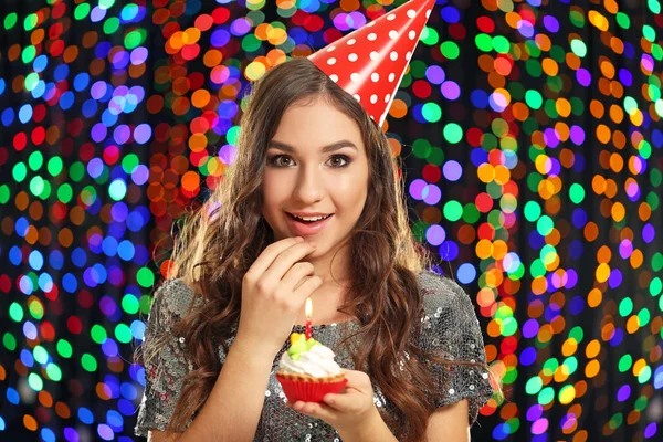Ung Kvinna Födelsedag Cap Håller Cupcake Med Ljus Ljus Bakgrund — Stockfoto