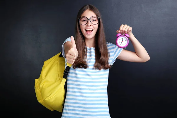 Junges Mädchen Mit Rucksack Und Wecker Zeigt Daumen Nach Oben — Stockfoto