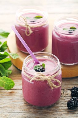 Böğürtlen yoğurt şişelerde gri ahşap tablo