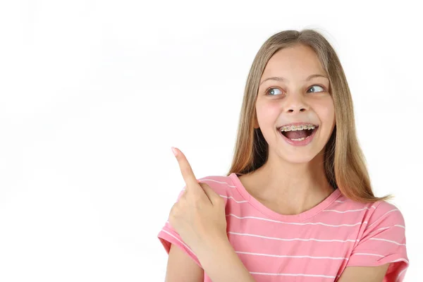 年轻的微笑的女孩与牙齿括号指向白色背景的手指 — 图库照片