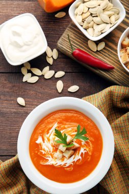 Balkabağı çorbası ekşi krema, Peksimet ve plaka üzerinde ahşap masa maydanoz ile