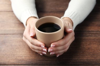 Kahve ahşap masa üzerinde tutan eller