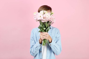 Pembe bir arka plan üzerinde eustoma çiçekli genç çocuk