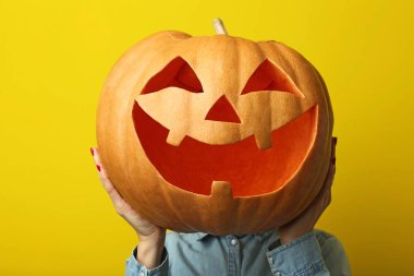 Cadılar Bayramı Balkabağı sarı arka plan üzerinde tutan erkek eller