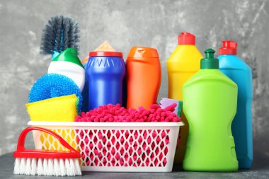 Şişe ile deterjan ve temizlik araçları gri arka plan üzerinde