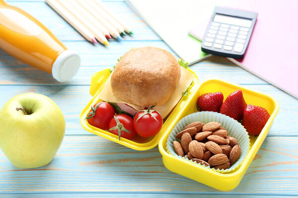 School lunch box with sandwich and bottle of juice on wooden table