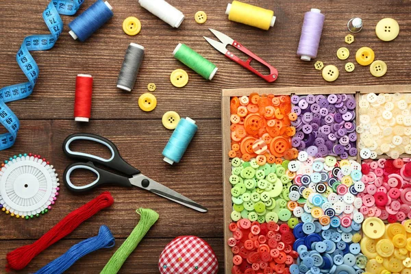 Colorful buttons in basket with sewing accessories on brown wooden table