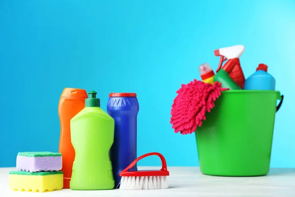 Bottles with detergent and cleaning tools on blue background