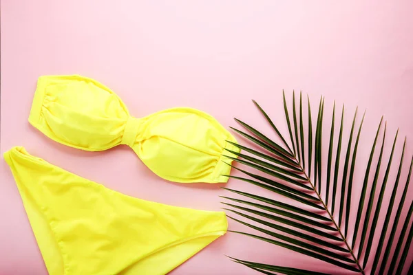Yeşil palmiye yaprağı pembe bir arka plan üzerinde sarı mayo
