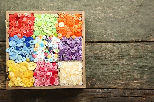 Colorful sewing buttons in basket on wooden table