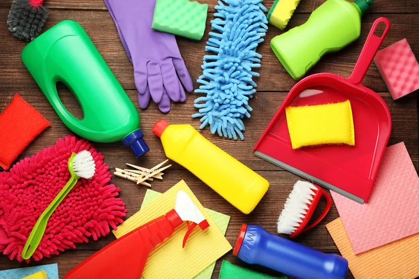 Bottles with detergent and cleaning tools on wooden table