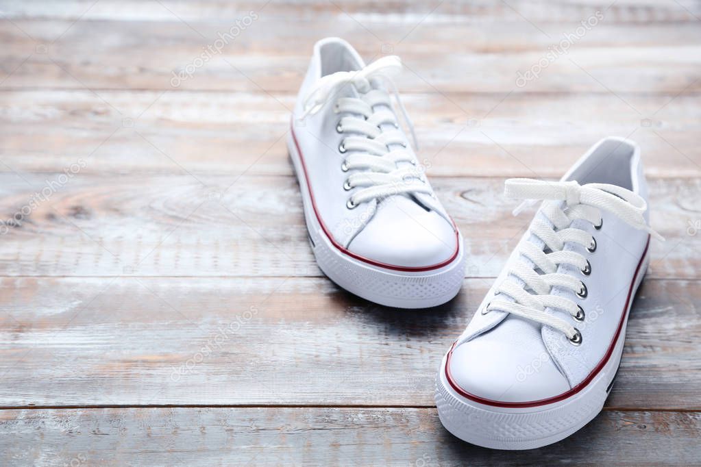 Pair of white sneakers on blue wooden table