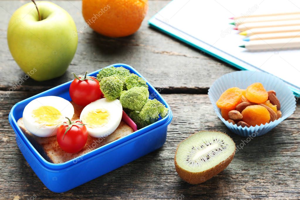 School lunch box with sandwich and eggs on wooden table