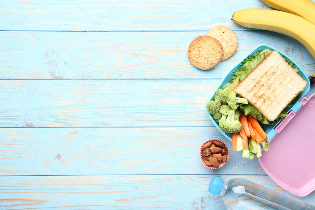 School lunch box with sandwich and vegetables on wooden table