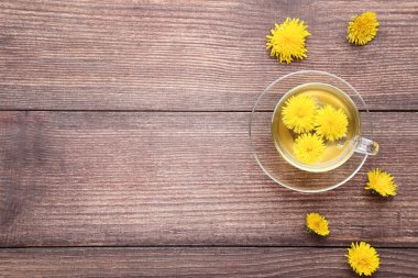 Kahverengi ahşap tabloda çay ile sarı karahindiba