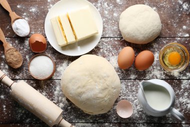 Tereyağı, yumurta ve süt kabı ahşap masa üzerinde çiğ hamur