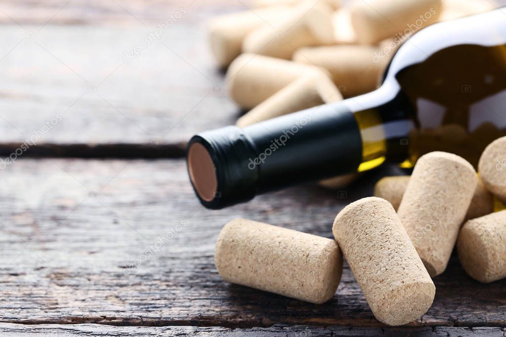 Wine bottle with corks on grey wooden table