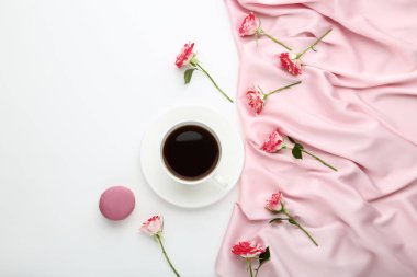 Fincan kahve ve saten kumaş üzerine beyaz arka plan ile gül çiçek