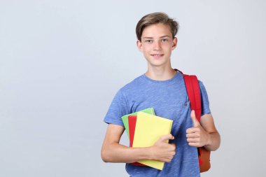 Sırt çantası ve gri arka plan üzerine kitaplar genç çocuk