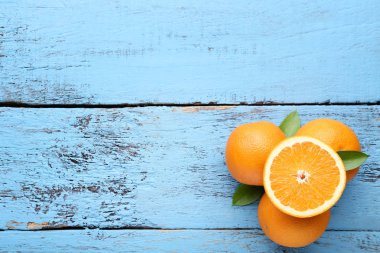 taze bütün ve yeşil ile yarıya portakal yapraklar üzerinde mavi ahşap masa