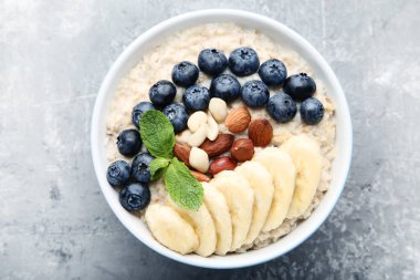 Çilek ve gri arka plan üzerinde kase fındık ile yulaf ezmesi