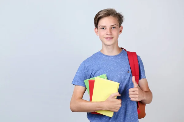Kleiner Junge Mit Rucksack Und Büchern Auf Grauem Hintergrund — Stockfoto
