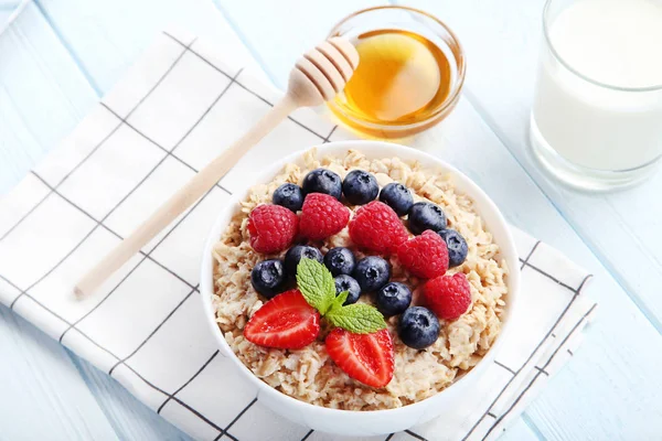 Oatmeal with berries and honey in bowl on checkered napkin