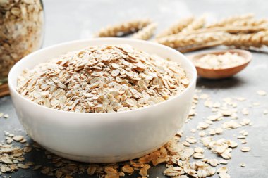 gri arka plan üzerinde beyaz kase çiğ yulaf ezmesi Kuru