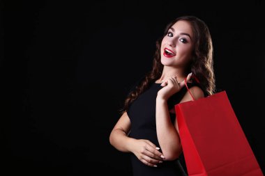 Siyah zemin üzerine kırmızı alışveriş çantası ile mutlu kadın