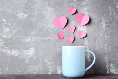 İçki gri arka plan üzerinde pembe kağıt yürekleri fincan