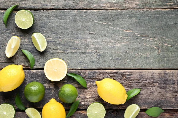 Lemons and limes with green leaves on grey wooden table