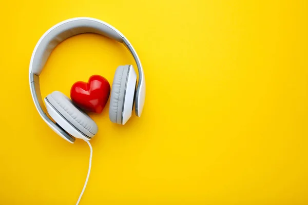 White headphones with red heart on yellow background
