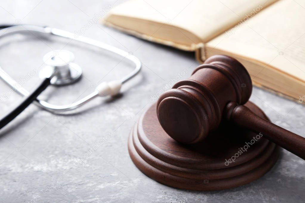 Judge gavel with stethoscope and book on grey background