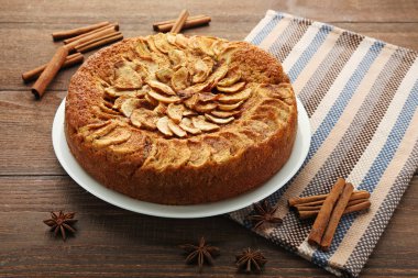 Elma pasta plaka üzerinde kahverengi ahşap masa peçete ve baharat ile